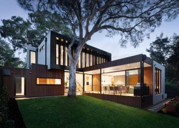 Modern two-story home with floor-to-ceiling windows lit up at dusk
